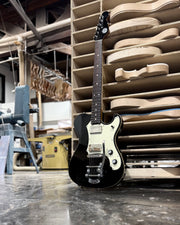 Full view of black Veritas Portlander guitar with cream binding and Bigsby